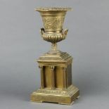 A Victorian gilt metal urn of campanula form raised on a rectangular base supported by columns