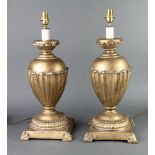 A pair of gilt resin table lamps of urn form and leaf decoration, raised on square bases, 43cm h x
