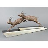 An Art Deco spelter and 2 colour marble figure group of 2 leaping gazelles raised on a shaped marble