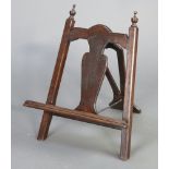 A 1930's Queen Anne style folding oak easel/book press with splat back and finials to the sides 56cm