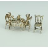 A cast silver model of 2 angels sitting at a table laid for tea together with a chair 41.5 grams,