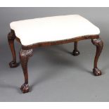 A 1920's carved Chippendale style mahogany stool of serpentine outline with overstuffed seat, raised