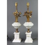 A pair of gilt metal ceramic and white marble table lamps raised on square marble bases marked Pauls