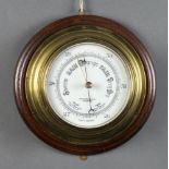 An aneroid barometer and thermometer with enamelled dial contained in a brass case, the dial