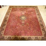 A red and white machine made floral patterned Persian style rug with central medallion 355cm x 275cm
