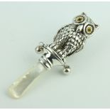 A repousse silver Victorian style rattle in the form of an owl with glass eyes and bells, mother