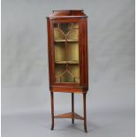 An Edwardian inlaid mahogany corner cabinet with raised back, fitted shelves enclosed by astragal