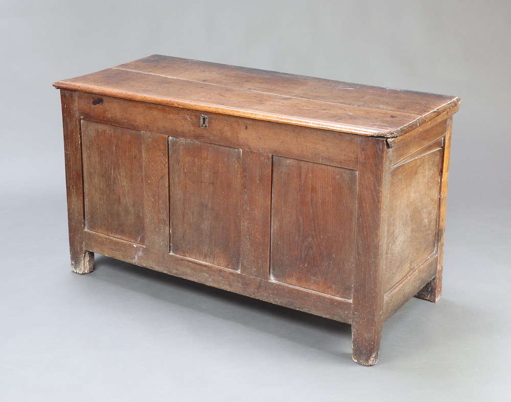 A 17th/18th Century oak coffer of panelled construction and hinged lid, the interior fitted a candle