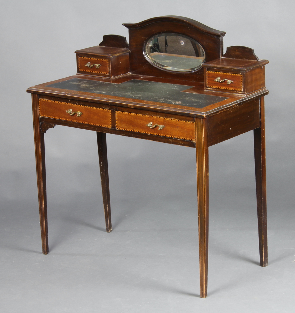 An Edwardian inlaid mahogany writing table, the arched back fitted an oval bevelled plate mirror