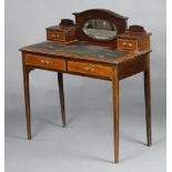 An Edwardian inlaid mahogany writing table, the arched back fitted an oval bevelled plate mirror