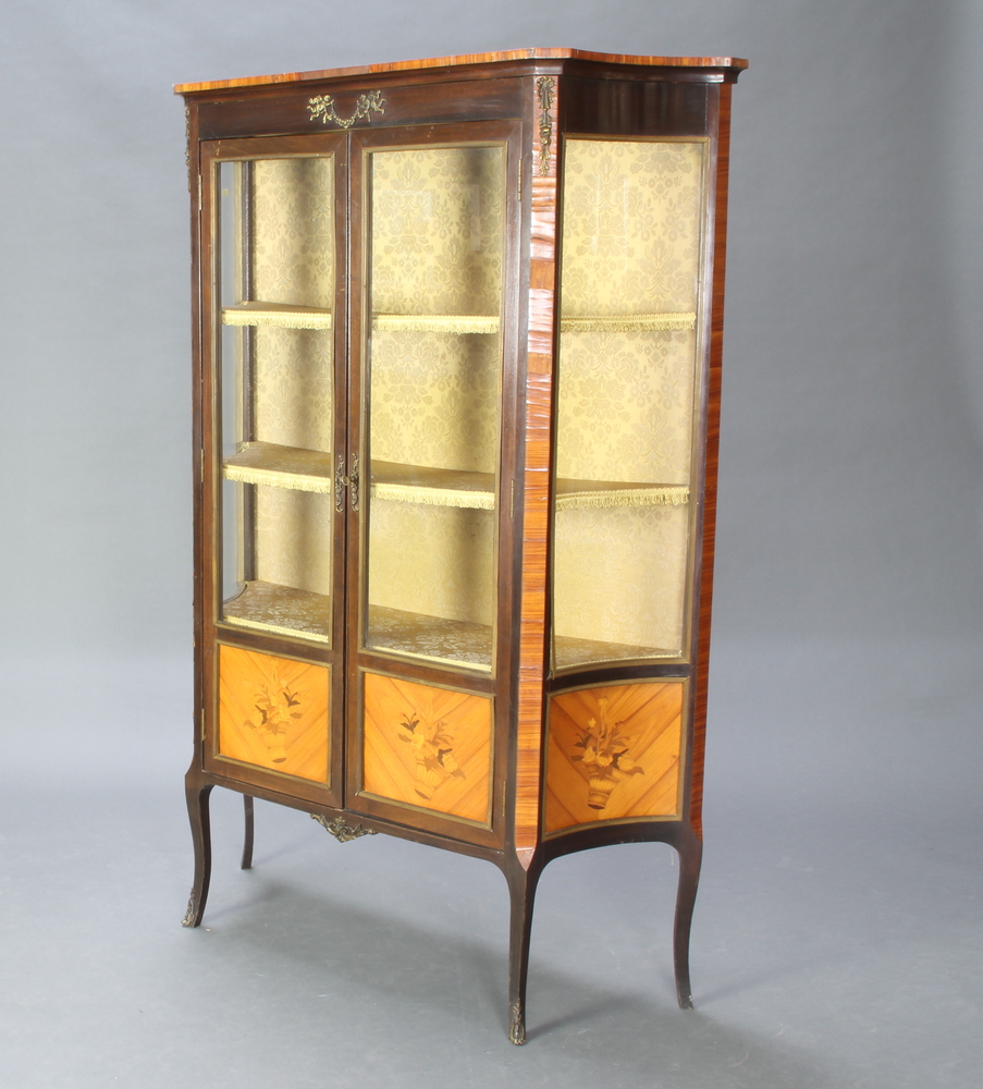 A French style Kingwood display cabinet of serpentine outline, fitted shelves enclosed by glazed