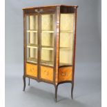 A French style Kingwood display cabinet of serpentine outline, fitted shelves enclosed by glazed