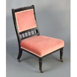 A Victorian ebonised nursing chair with bobbin turned decoration, the seat and back upholstered in
