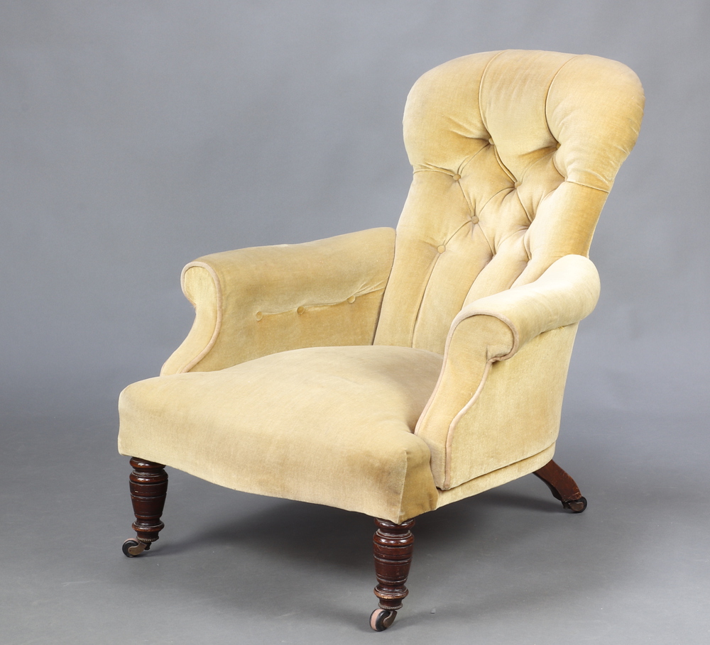 A Victorian armchair upholstered in yellow buttoned material, raised on turned supports 88cm h x