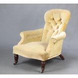 A Victorian armchair upholstered in yellow buttoned material, raised on turned supports 88cm h x
