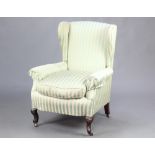 An Edwardian winged armchair upholstered in Regency stripe, raised on cabriole supports 100cm h x