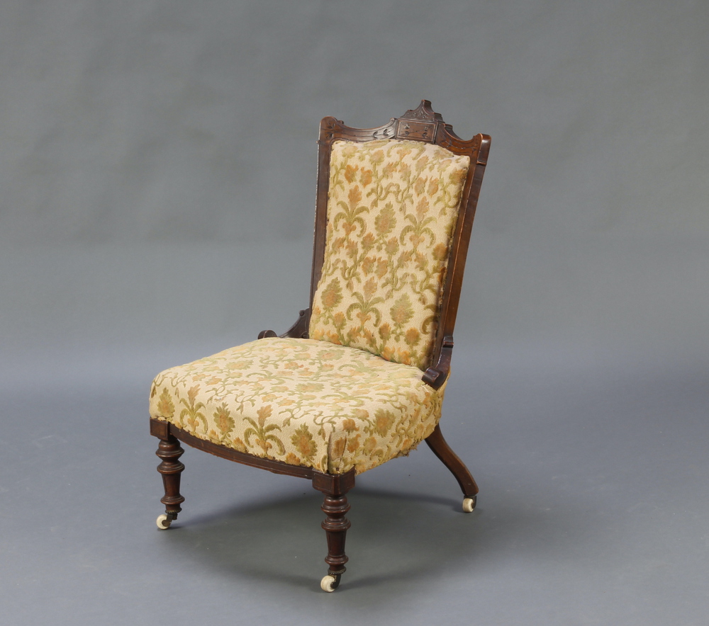 A Victorian carved walnut showframe nursing chair upholstered in yellow sculptured material,