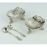 A pair of Victorian style cast silver table salts in the form of shells, raised on dolphin feet with