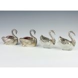 A pair of silver plated salts in the form of swans with cranberry glass liners 9cm together with a