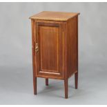 An Edwardian mahogany bedside cabinet with crossbanded top, enclosed by a panelled door, raised on