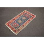 A blue, green and brown ground Caucasian style rug with 4 stylised medallions to the centre within a