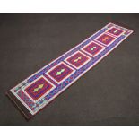 A blue, white and red ground Suzni Kilim runner with 6 rectangular panels to the centre 303cm x 67cm