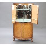 A 1930's bleached figured walnut bow front corner cocktail cabinet, the upper section with