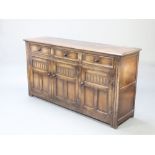 An Ipswich style carved oak dresser base fitted 3 drawers above triple cupboard with arcaded