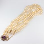 A triple strand cultured pearl necklace with a 9ct yellow gold amethyst and seed pearl clasp 43cm,