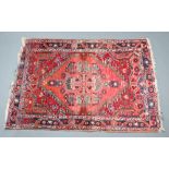 A red and green Afghan rug with diamonds to the centre 129cm x 103cm Some wear