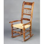 A 19th Century elm and beech ladder back rocking chair with spindle turned decoration and woven rush
