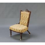 A Victorian carved walnut showframe nursing chair upholstered in yellow sculptured material,
