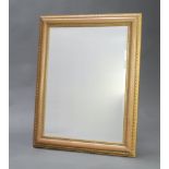 A 20th Century rectangular bevelled plate wall mirror contained in a decorative gilt frame 75cm h