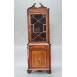 An Edwardian inlaid mahogany double corner cabinet with shaped pediment, fitted shelves enclosed