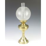 A gilt metal oil lamp with clear glass chimney and etched glass shade, raised on a reeded column