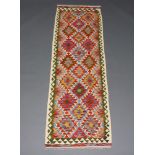 A white, purple, turquoise and green ground Chobi Kilim runner with all over geometric design