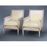 A pair of Empire style white and gilt painted armchairs upholstered in yellow material, raised on