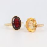 A yellow metal stamped 18k citrine ring, 6.8 grams, size M together with a garnet ditto 4.6 grams