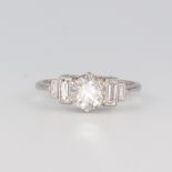 A white metal stamped plat diamond ring, the circular brilliant cut stone 1.02ct, the 4 baguette