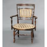 An Edwardian mahogany framed open arm chair with upholstered seat and back raised on turned supports