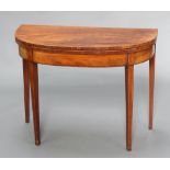 An inlaid Georgian mahogany demi-lune card table raised on square tapered supports ending in spade