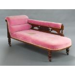 A late Victorian carved mahogany show frame chaise longue upholstered in pink material, raised on