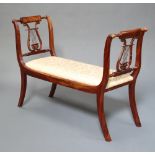 A Regency style mahogany window seat with lyre decoration and upholstered seat, raised on scroll