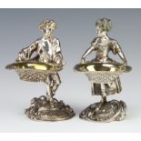 A pair of Victorian style cast silver plated salts in the form of a standing lady and gentleman,