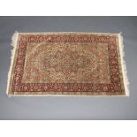 A fine Turkish green and red ground silk floral patterned rug with central medallion and border