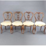A set of 4 Victorian walnut balloon back chairs with carved splats and overstuffed seats raised on