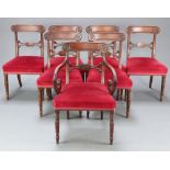 A set of 7 Regency bar back dining chairs with carved mid rails and over stuffed seats, raised on