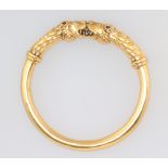 A yellow metal bangle with leopards head terminals 75mm diam., 32 grams