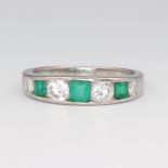 A white metal stamped 750 emerald and diamond ring, the 3 princess cut emeralds 0.4ct, the 3