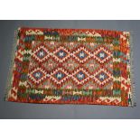 A white, green, red and turquoise Chobi Kilim rug with all over geometric design 124cm x 84cm